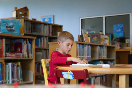 Young boy sitting at a table at the library working on a puzzleの写真素材