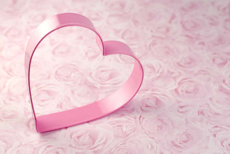 Pink heart cookie cutter isolated on pink rose background with copy spaceの写真素材