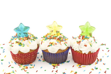 Colorful cupcakes with candy stars and multicolored sprinkles on a horizontal white background with copy spaceの写真素材