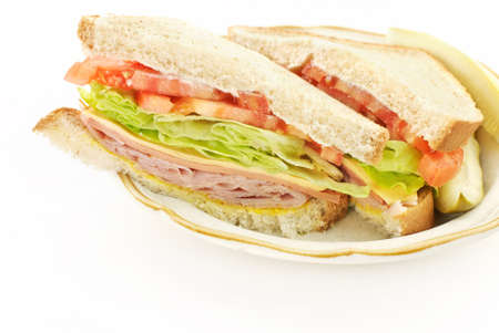 A delicious healthy ham, cheese and bologna sandwich, cut in half on a plate, white copy spaceの写真素材