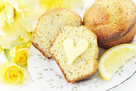 A plate with fresh baked lemon poppy seed muffins with heart shaped butter on muffin, conceptの写真素材