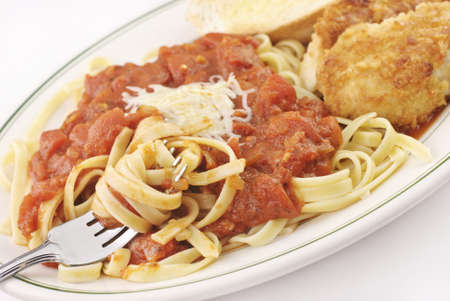 A plate full of fettucini with homemade marinara sauce and parmesan crusted chicken, selective focus on fork, deliciousの写真素材