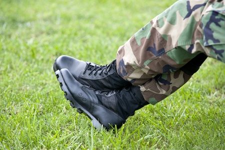 A US Army soldier wearing camouflage resting with just a closeup of his legs and boots, selective focus on bootsの写真素材