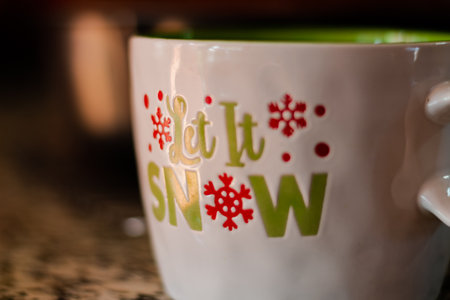 A warm scene of a Christmas mug on a counter in a darkly lit room with depth of field.の写真素材