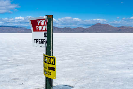 An old and warn, No Trespassing / caution sign on the salt flats of Utah, America with a mountain range on the horizon.の写真素材