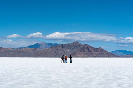 A group of friends and tourists sightseeing in the distance, on the glistening white salt flats of Utah, United States.の写真素材