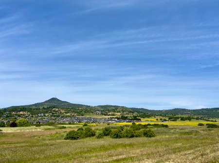 Beautiful panoramic view of meadows and fields with yellow wildflowers and green grass and Roxyann hill on the horizon, Southern Oregon, Pacific Northwest.の写真素材