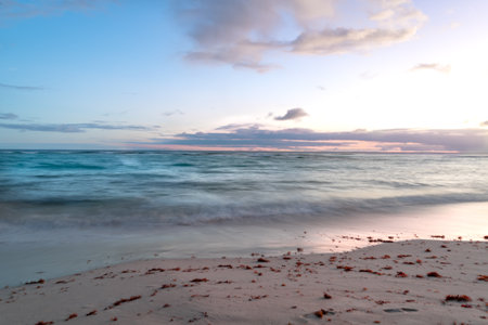 Long exposure with soft turquoise waves wash up on the sands of Barbados island with a pink evening sunset.の写真素材