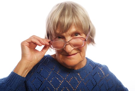 old senior lady looking through her eyeglasses isolated on white backgroundの写真素材