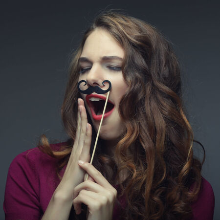 Girl wearing fake mustaches. Ready for party.の写真素材