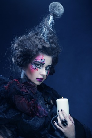 Young woman with creative make up holding candle. Halloween theme.の写真素材