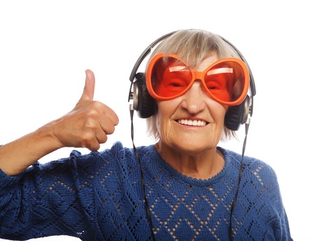 Funny old lady listening music and showing thumbs up. Isolated on white.の写真素材