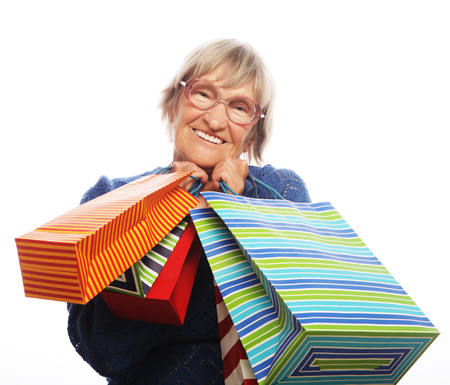 Happy senior woman with shopping bags isolated on whiteの写真素材