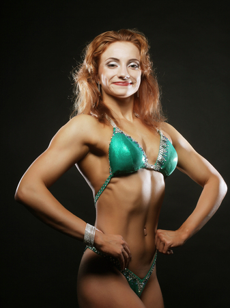A beautiful woman bodybuilder posing in green  bikiniの写真素材