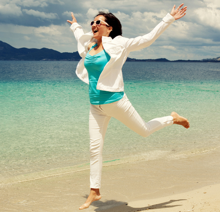 Happy girl jumping on the beach, summer holidayの写真素材