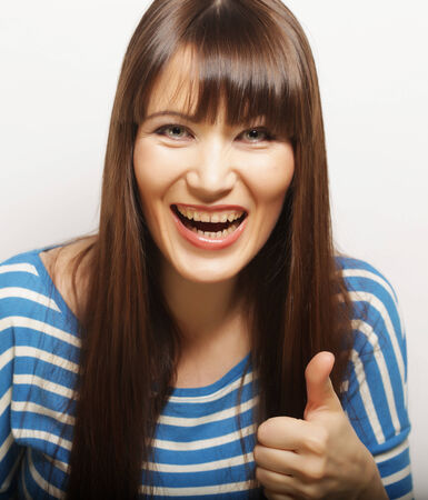 Happy smiling beautiful young woman showing thumbs up gestureの写真素材