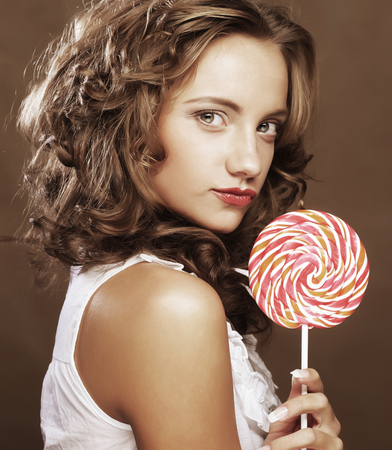 pretty happy curly  girl with a lollipop in her handの写真素材