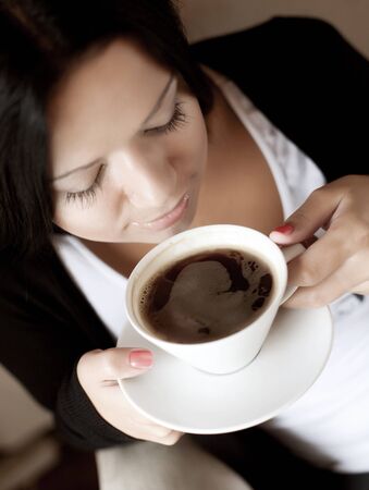 beautiful young woman sitting in a cafe drinking coffee\r\rの写真素材