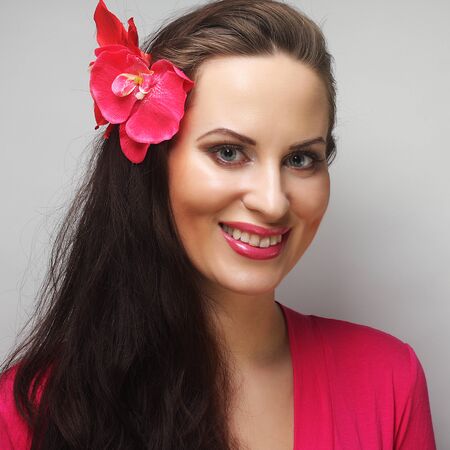 young happy woman with pink flower in the hairの写真素材