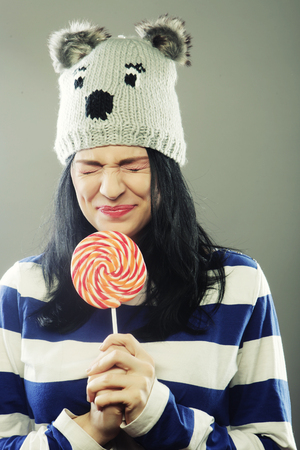 funny woman with winter hat holding big lollipopの写真素材
