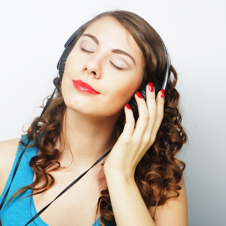 Young curly woman with headphones listening music.Studio shot.の写真素材