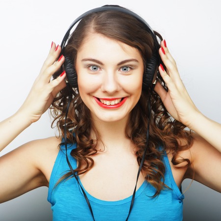 Young curly woman with headphones listening music.Studio shot.の写真素材