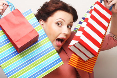 beautiful young woman with colored shopping bags over grey backgroundの写真素材