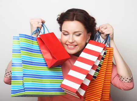 beautiful young woman with colored shopping bags over grey backgroundの写真素材