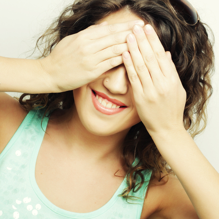 Young woman covering her eyes with her hands.Studio shot.の写真素材