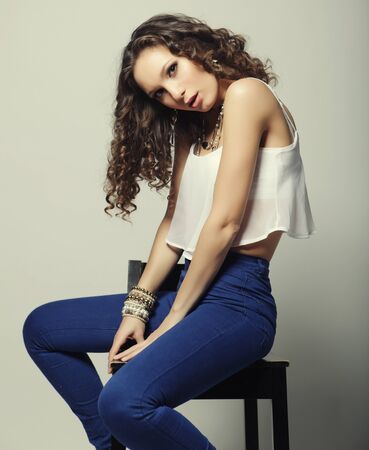 Young fashion model sitting on chair, studio shotの写真素材