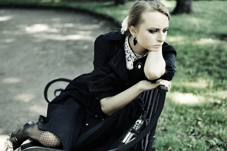 young woman sitting on a bench in parkの写真素材