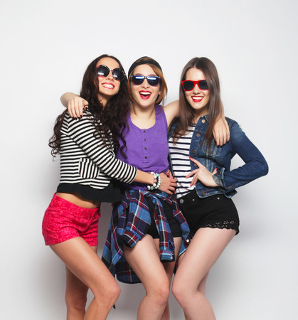 Three stylish sexy hipster girls best friends.Standing together and having fun. Looking at camera. Over gray background.の写真素材