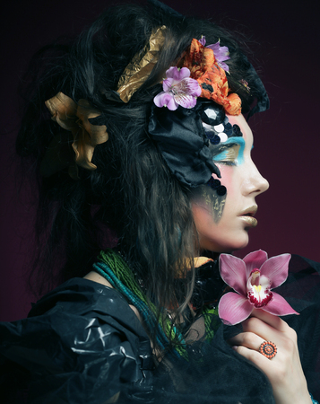 young woman with creative make up holding pink flowerの写真素材