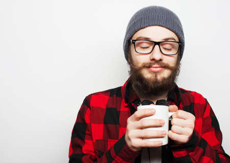 Food, happiness and people concept: young bearded man with a cup of coffee against grey の写真素材