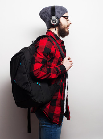 Life style, education and people concept:  young bearded man listening to music while standing against grey . Hipster style.の写真素材