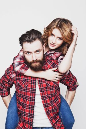 life style, happiness and people concept: Happy loving couple. Young man piggybacking his girlfriend. Studio shot over white background.Special Fashionable toning photos.の写真素材
