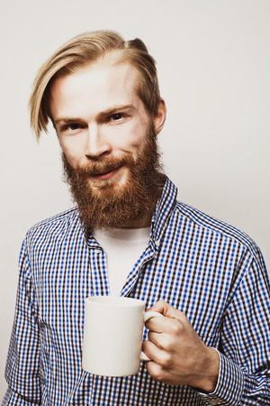 food, happiness and people concept: young bearded man with a cup of coffee against grey backgroundの写真素材