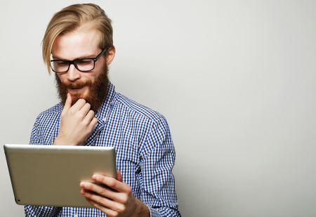 Tehnology, education and lifestyle concept: young man  using a tablet computer - over gray backgroundの写真素材