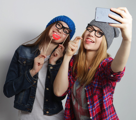 two young funny women taking selfie with mobile phoneの写真素材