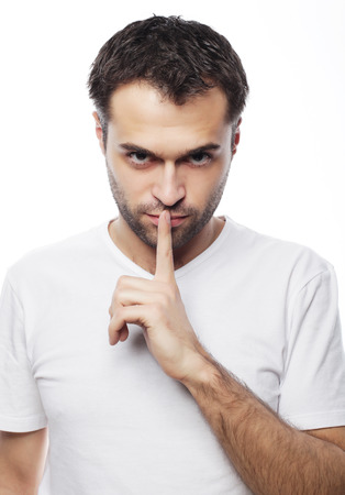 life style  and people concept: young man wearing white t-shirt making silence gesture, shhhhh!!の写真素材