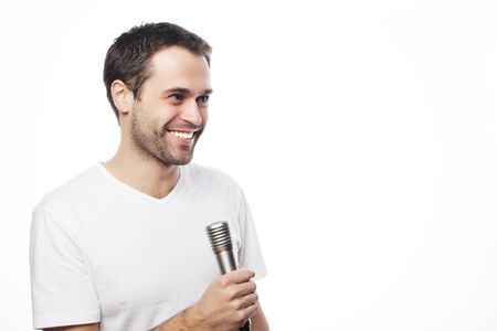 Life style, people and leasure concept: a young man wearing a white shirt holding a microphone and singing. Isolated on white.の写真素材