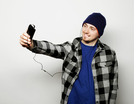 life style, education and people concept: young  man listening to music and using smartphone, while...