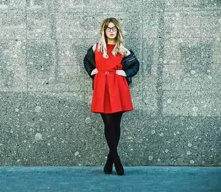Fashion portrait of hipster woman in stylish casual summer outfit posing against wall background.の写真素材