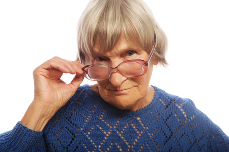 old senior lady looking through her eyeglasses isolated on white backgroundの写真素材