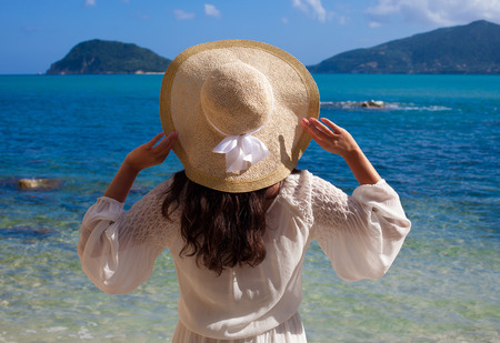 Young woman in summer dress with  straw hat looking to a sky and seaの写真素材