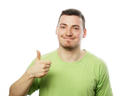 life style  and people concept: happy young man in green shirt  showing thumbs up. Isolated on white.の写真素材