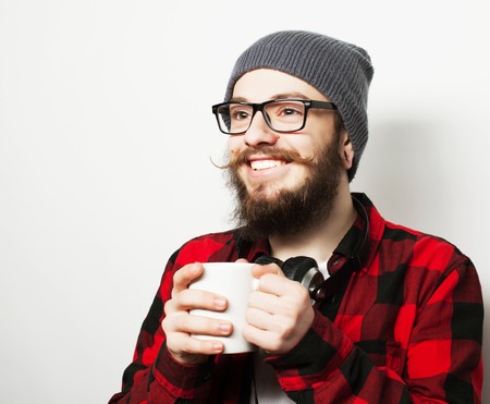 food, happiness and people concept: young bearded man with a cup of coffee against grey background