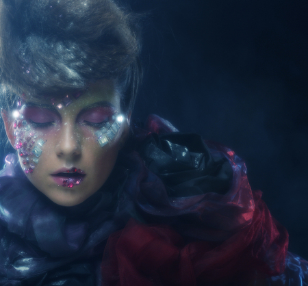 portrait of woman with artistic make-up in blue smokeの写真素材