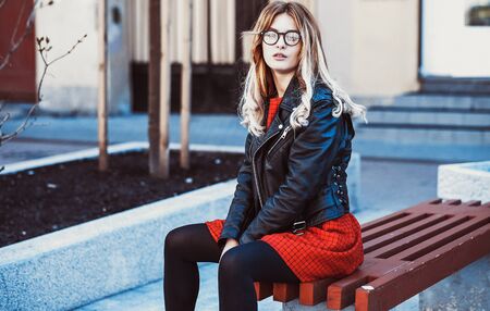 Girl Sitting on Bench. Street Fashion. Urban Lifestyle. Young Beautiful Woman Walking Outdoor.Image toned.の写真素材