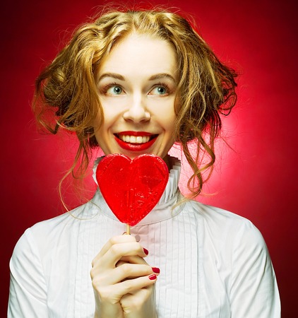 attractive woman with heart caramel over red backgroundの写真素材